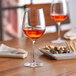Two Nude Refine wine glasses filled with wine on a table.