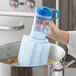 A hand holding a blue Vigor Polar Paddle in a pot of liquid.