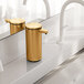 A Simplehuman brass stainless steel touchless sensor soap dispenser on a counter.