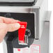 A hand pressing a red button on a Bloomfield airpot coffee brewer.