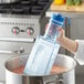 A hand holding a Vigor Polar Cooling Paddle with ice in a pot of liquid.