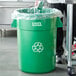 A man standing next to a green Lavex recycling can with a plastic bag over it.