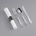 A pre-rolled white napkin with metallic silver heavy weight cutlery set including a spoon and knife.