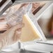 A gloved hand holds a piece of cheese in a Choice vacuum packaging pouch.