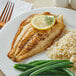 A plate with catfish, rice, and green beans with a lemon slice on top.