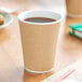 A brown beverage in a Choice double wall ripple paper hot cup on a table.