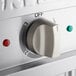 A close up of a white control knob on a ServIt electric steam table.