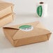 A brown box with a roll of green TamperSafe labels next to a roll of paper towels.