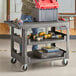 A man standing next to a Lavex utility cart with tools on it.