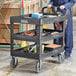 A man pushing a Lavex black utility cart with tools on it.