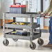 A man pushing a Lavex gray utility cart with tools.