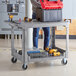 A man standing next to a Lavex large gray utility cart with tools on it.