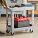 A man pushing a Lavex medium gray utility cart with tools.