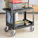 A man standing next to a Lavex black utility cart with tools on it.