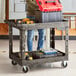 A man standing next to a Lavex black utility cart with a red tool box on it.