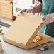 A person in gloves holding a Choice kraft pizza box.