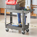 A man standing next to a Lavex medium gray utility cart with a tool box on it.