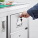 A hand using a key to lock a drawer on a Regency stainless steel work table.