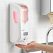 A white San Jamar Summit Rely hybrid automatic hand soap, sanitizer, and lotion dispenser on a wall.