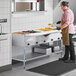 A man in a commercial kitchen using a ServIt natural gas steam table.