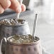 A person using an Acopa stainless steel straw in a metal mug of ice.