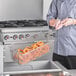 A chef holding a 16 7/8" x 8 1/4" x 6 1/8" fryer basket.