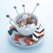 An Arcoroc saucer with sugar cubes, marshmallows, and sticks on a table.