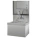 A stainless steel Advance Tabco hand sink with a paper towel dispenser and faucet above a cabinet with a door.