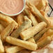 A basket of breaded and fried vegetable sticks served with a dipping sauce.