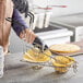 A person holding a metal double taco fry basket with tortillas inside.