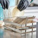 A person in black gloves using a Choice steel tostada fry basket to cut tortillas.