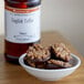 A bowl of chocolate covered toffee with nuts.