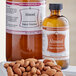 A bottle of LorAnn Oils Almond Bakery Emulsion on a counter next to a bowl of almonds.