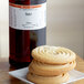 A stack of butter cookies on a plate next to a bottle of LorAnn Oils Butter Super Strength Flavor.