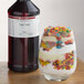 A glass of fruity dessert next to a bottle of LorAnn Oils Tutti-Frutti flavoring.