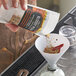 A hand pouring Rokz Bloody Mary seasoning into a glass using a white funnel.