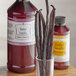 A glass jar of LorAnn Oils Butter Vanilla Bakery Emulsion next to a glass of vanilla beans.