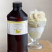 A bottle of LorAnn Oils Banana Cream flavor next to a glass of banana ice cream.