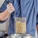 A person using a Choice stainless steel strainer to stir food into a pot.