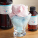 A bowl of cotton candy and two bottles of LorAnn Oils cotton candy flavoring.