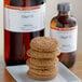 A stack of ginger cookies on a plate next to a bottle of LorAnn Oils ginger flavor.