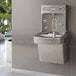 An Elkay light gray water bottle filling station attached to a wall above a sink.