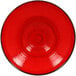 A red porcelain plate with a black rim.