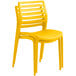 A close up of a yellow Lancaster Table & Seating Allegro stackable resin side chair.