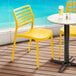 Two Lancaster Table & Seating yellow resin chairs on an outdoor deck.