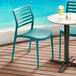 Two Lancaster Table & Seating Allegro teal resin chairs on a deck.