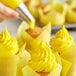 A hand using a pastry bag to pipe Rich's Yellow Buttrcreme Icing onto a cupcake.