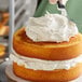 A person using a knife to cut a cake with Rich's White Buttrcreme Icing on top.