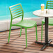 Two Lancaster Table & Seating Allegro Pistachio stackable resin side chairs on a deck.