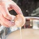 A person's hand holding a round transparent container of liquid.